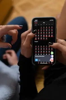 Close-up of hands interacting with a smartphone displaying a digital calendar app.